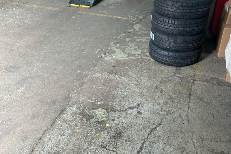 Cracked and damaged commercial garage floor in need of repair before epoxy resin coating application showing visible wear and surface imperfections