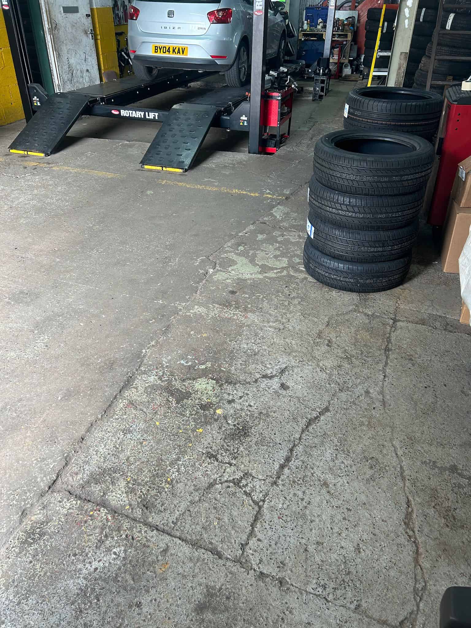 Cracked and damaged commercial garage floor in need of repair before epoxy resin coating application showing visible wear and surface imperfections