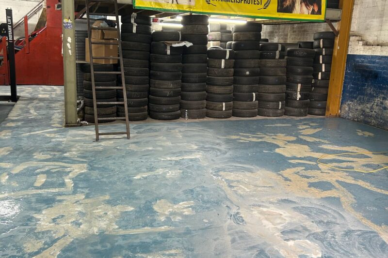 Commercial garage floor being prepared for epoxy resin coating, with surface cleaning, crack repair, and grinding to ensure a smooth and durable finish.