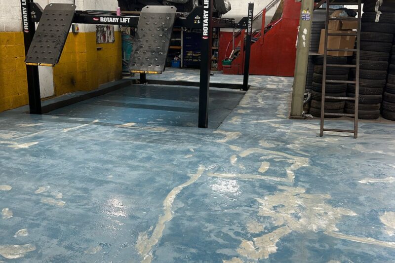 Commercial garage floor being prepared for epoxy resin coating, with surface cleaning, crack repair, and grinding to ensure a smooth and durable finish.