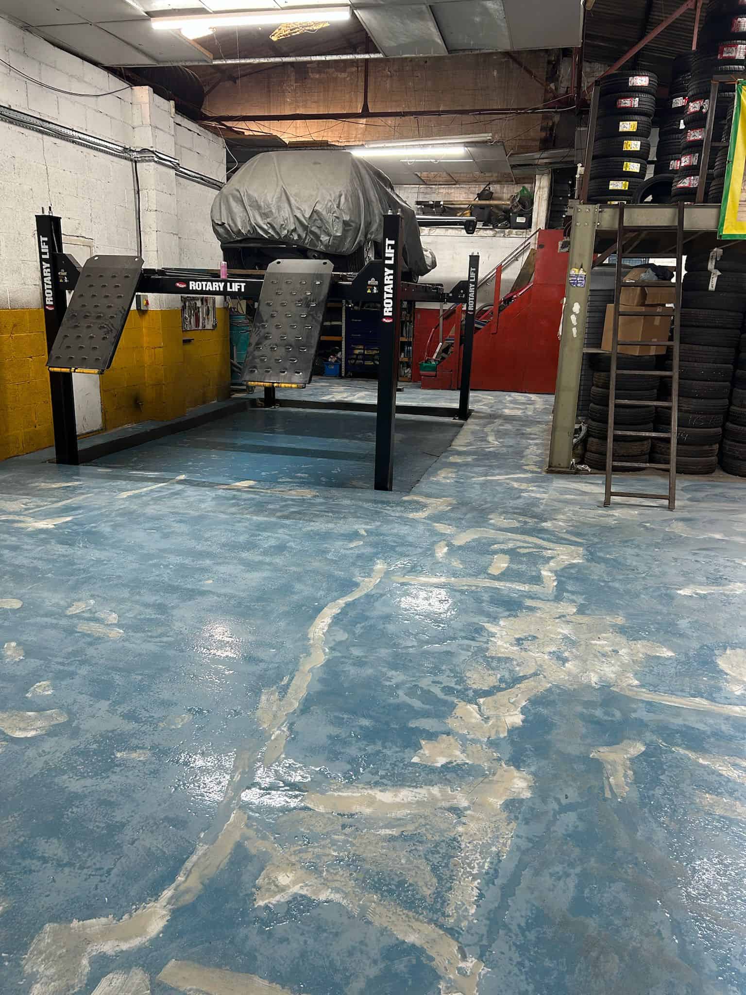 Commercial garage floor being prepared for epoxy resin coating, with surface cleaning, crack repair, and grinding to ensure a smooth and durable finish.