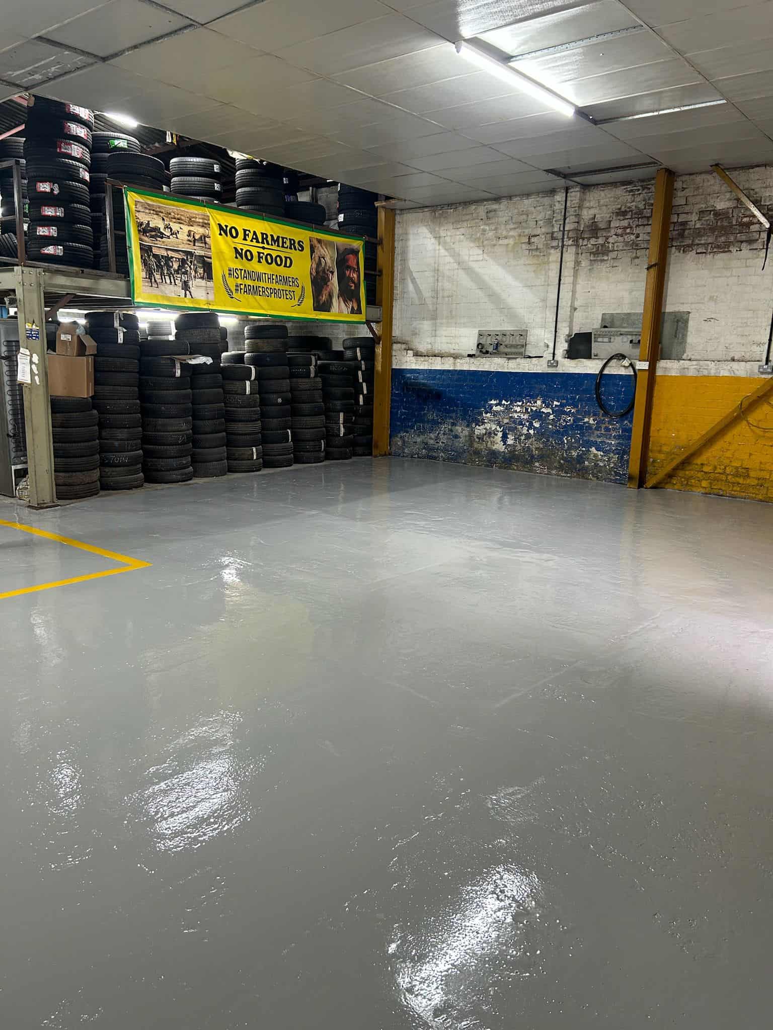 Finished commercial garage floor with a smooth, seamless epoxy resin coating and yellow safety line, providing a durable, professional surface ready for heavy-duty use.