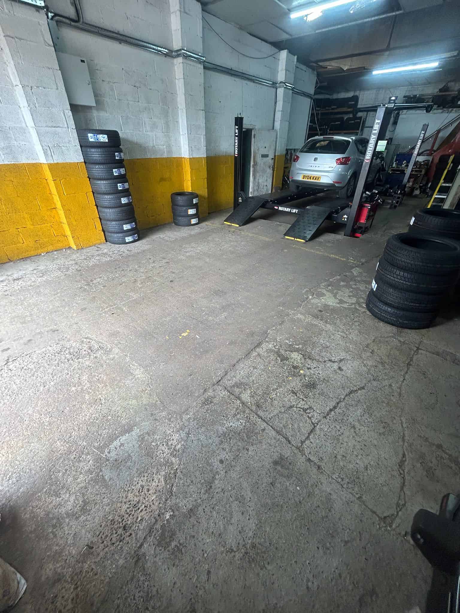 Cracked and damaged commercial garage floor in need of repair before epoxy resin coating application showing visible wear and surface imperfections